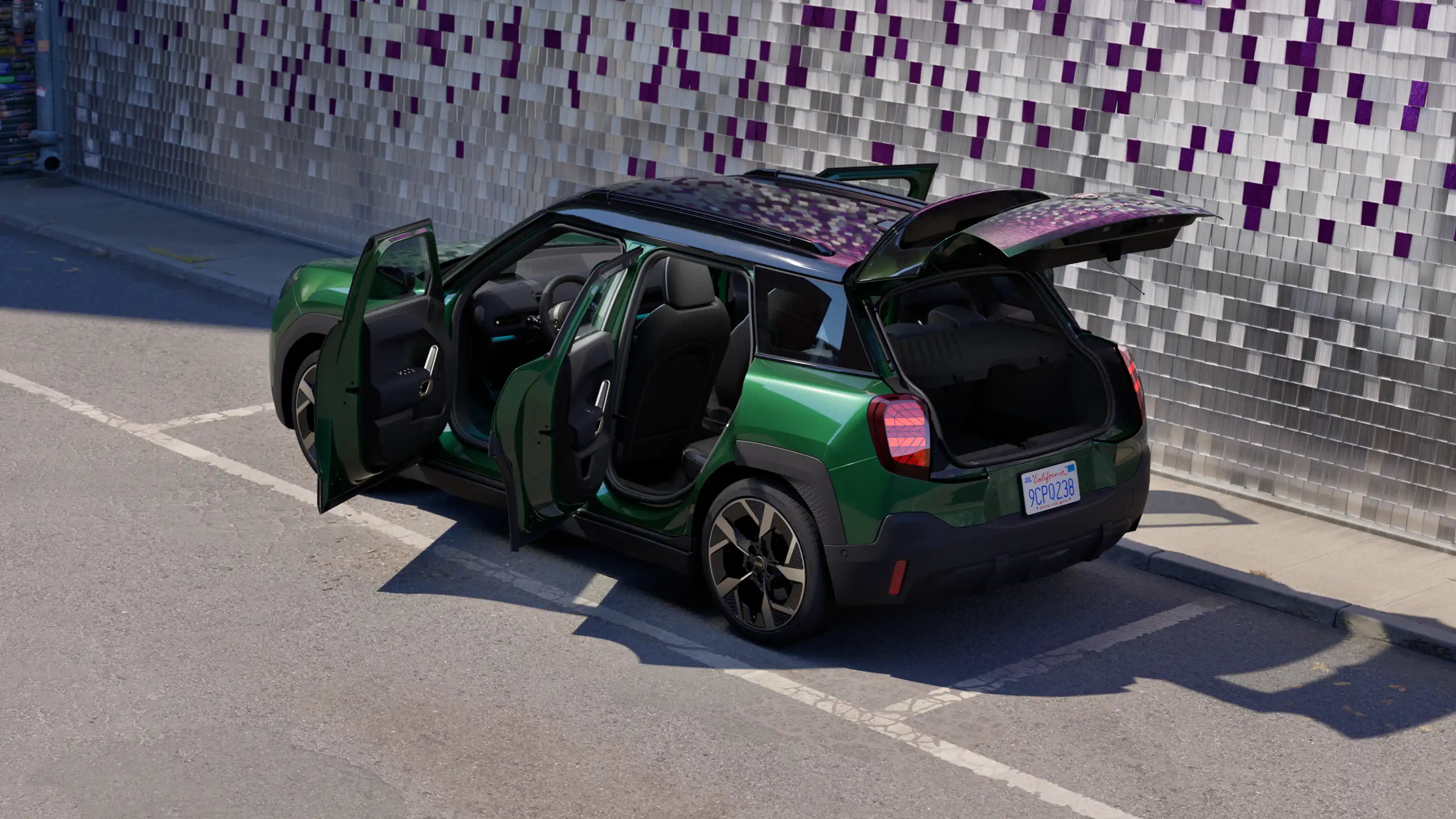 Achterkant van een MINI Aceman Electric in British Racing Green op een parkeerplaats met alle portieren open en een gekleurde muur op de achtergrond