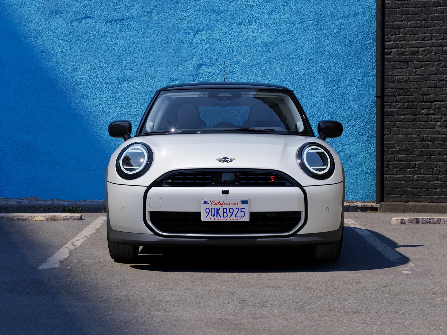 Vooraanzicht van een parkerende MINI Cooper in Nanuq White met dak in Black.