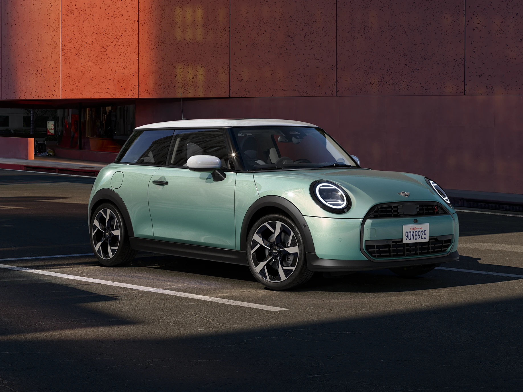 Zijaanzicht van de MINI Cooper in Ocean Wave Green met dak in White.