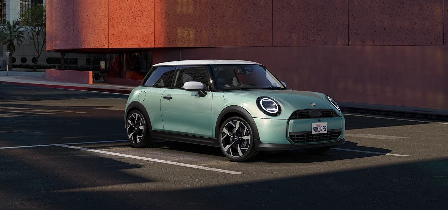 Zijaanzicht van de MINI Cooper in Ocean Wave Green met dak in White.