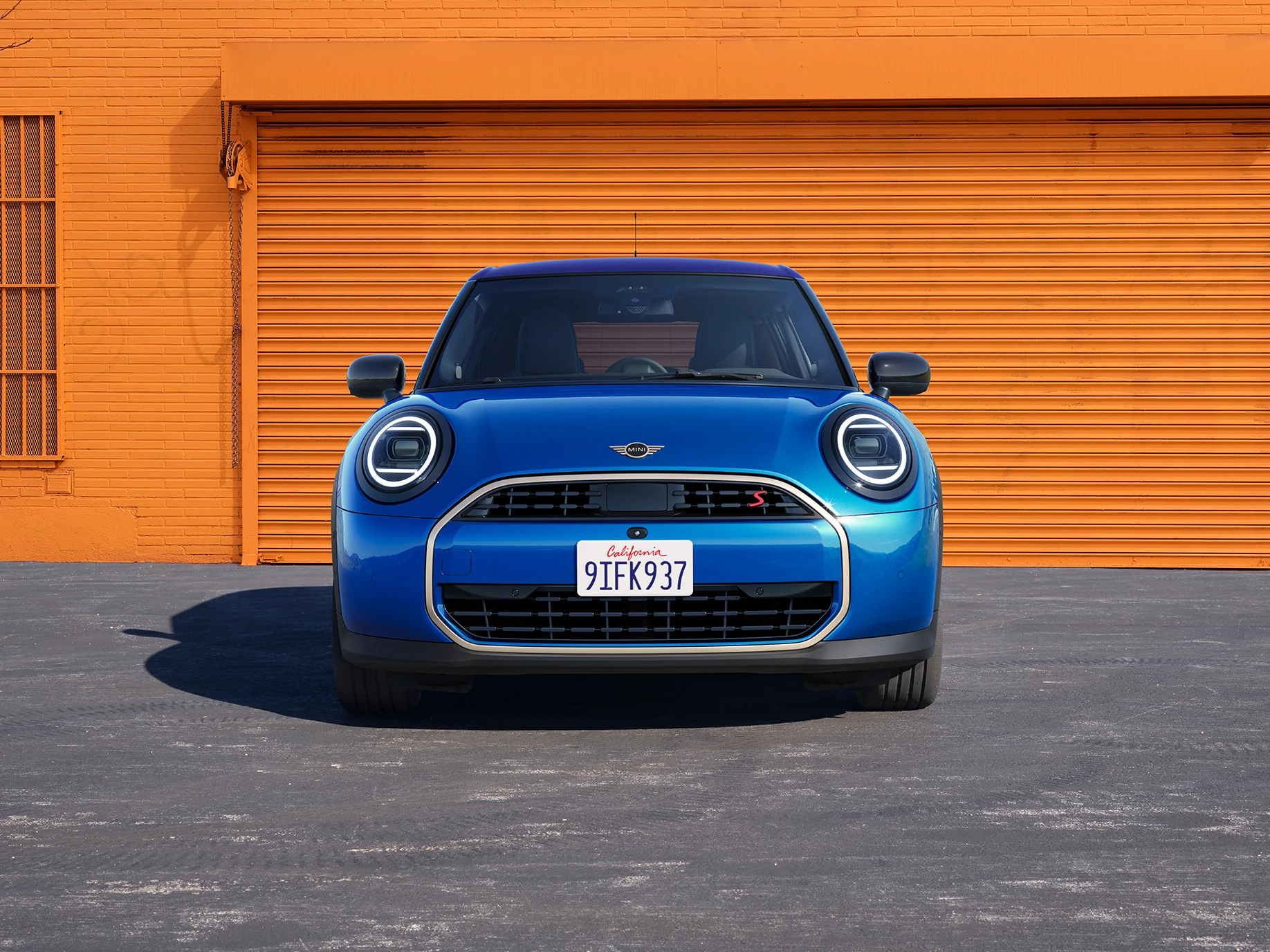 Vooraanzicht van de MINI Cooper 5-deurs in Icy Sunshine Blue met dak in Multitone Blue.