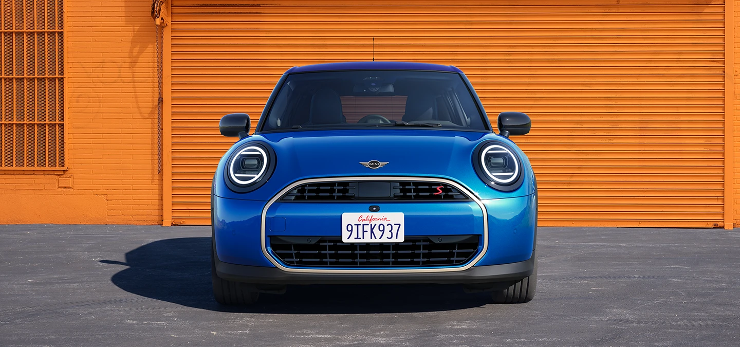 Vooraanzicht van de MINI Cooper 5-deurs in Icy Sunshine Blue met dak in Multitone Blue.
