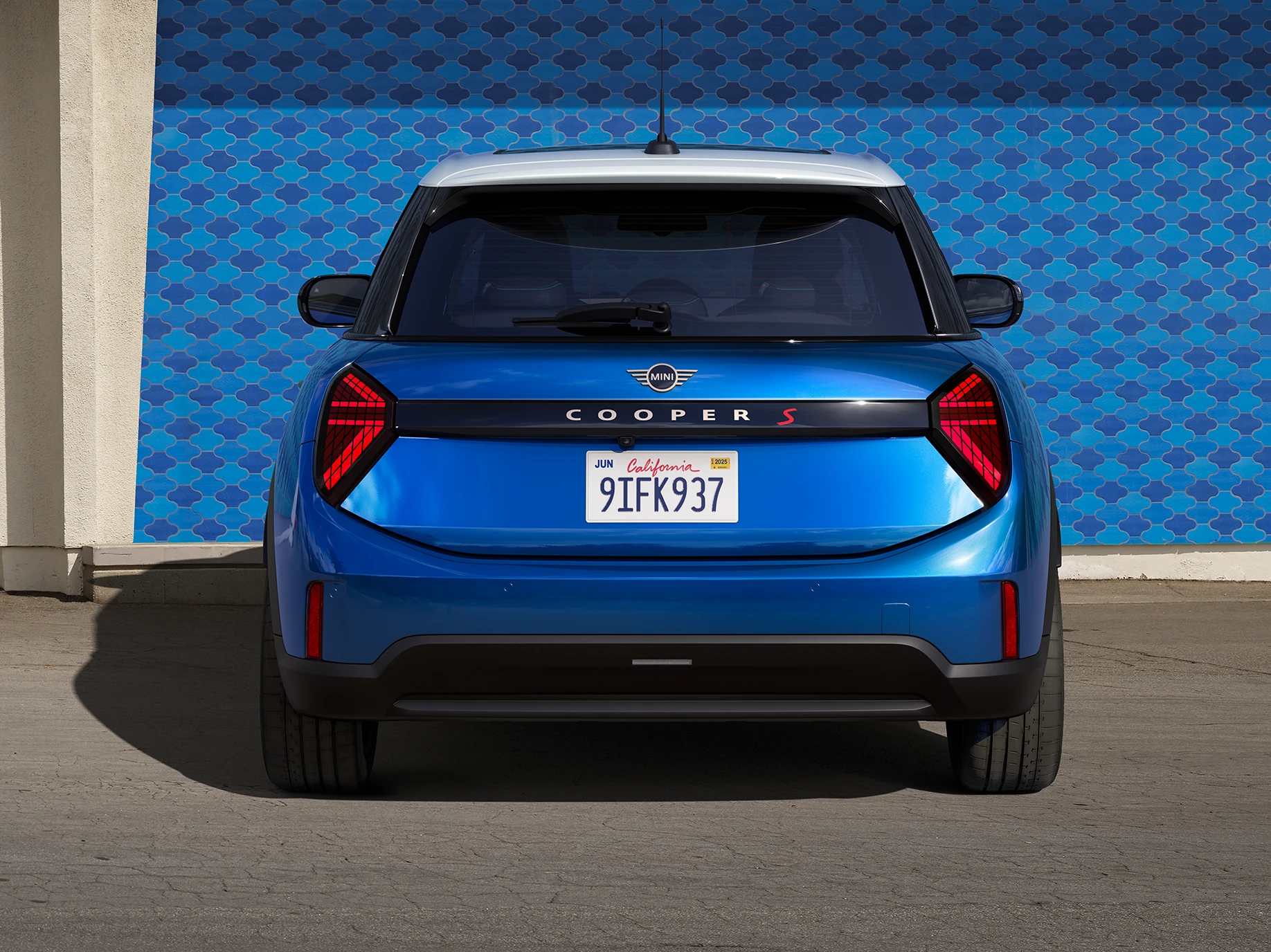 Achteraanzicht van de MINI Cooper 5-deurs in Icy Sunshine Blue met dak in Multitone Blue.