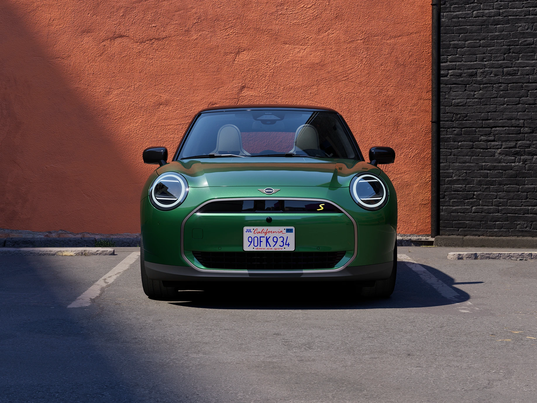 Vooraanzicht van een MINI Cooper Electric in British Racing Green met dak in Black.