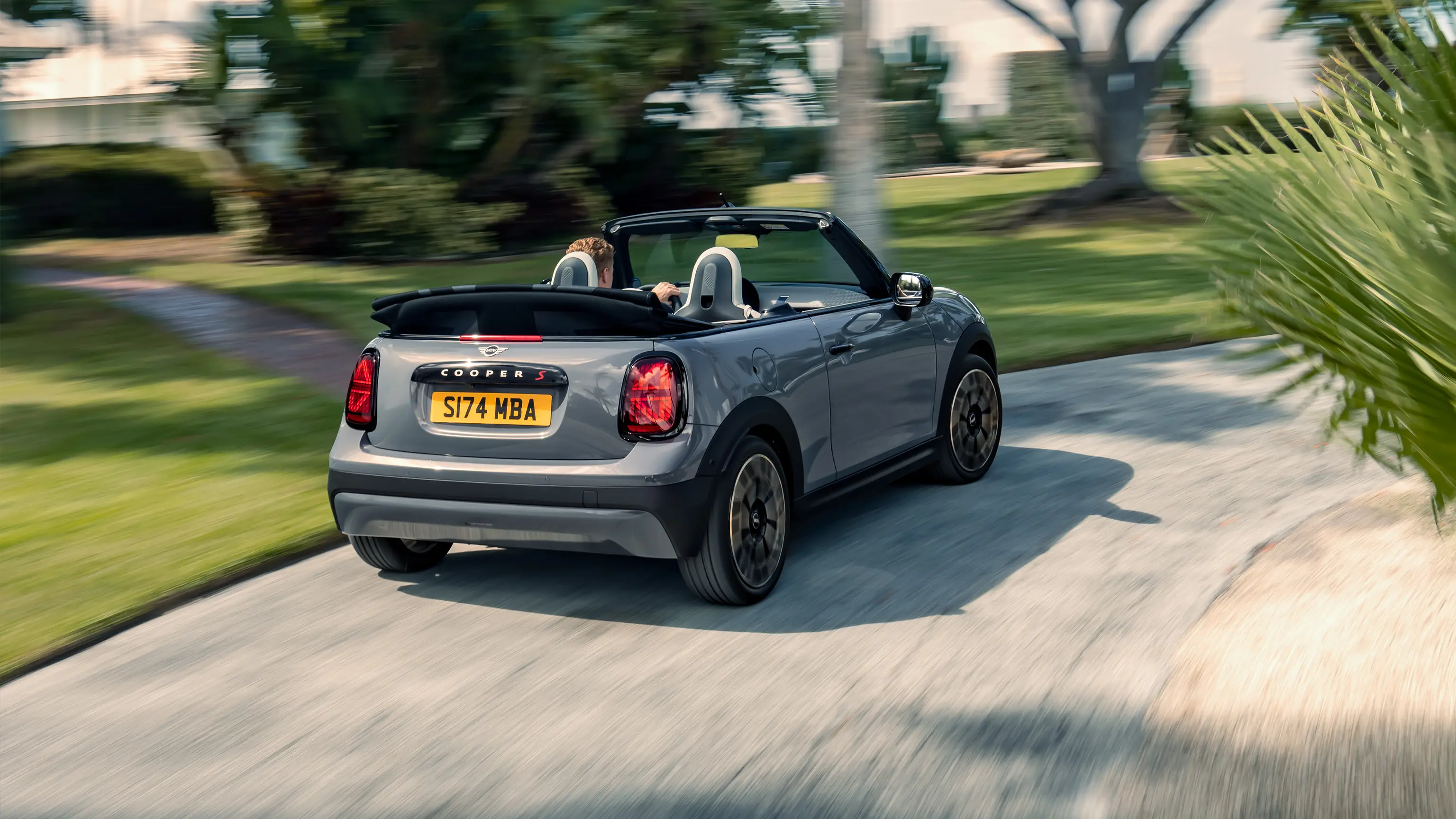Achteraanzicht van een rijdende MINI Cooper Cabrio in Copper Grey 
