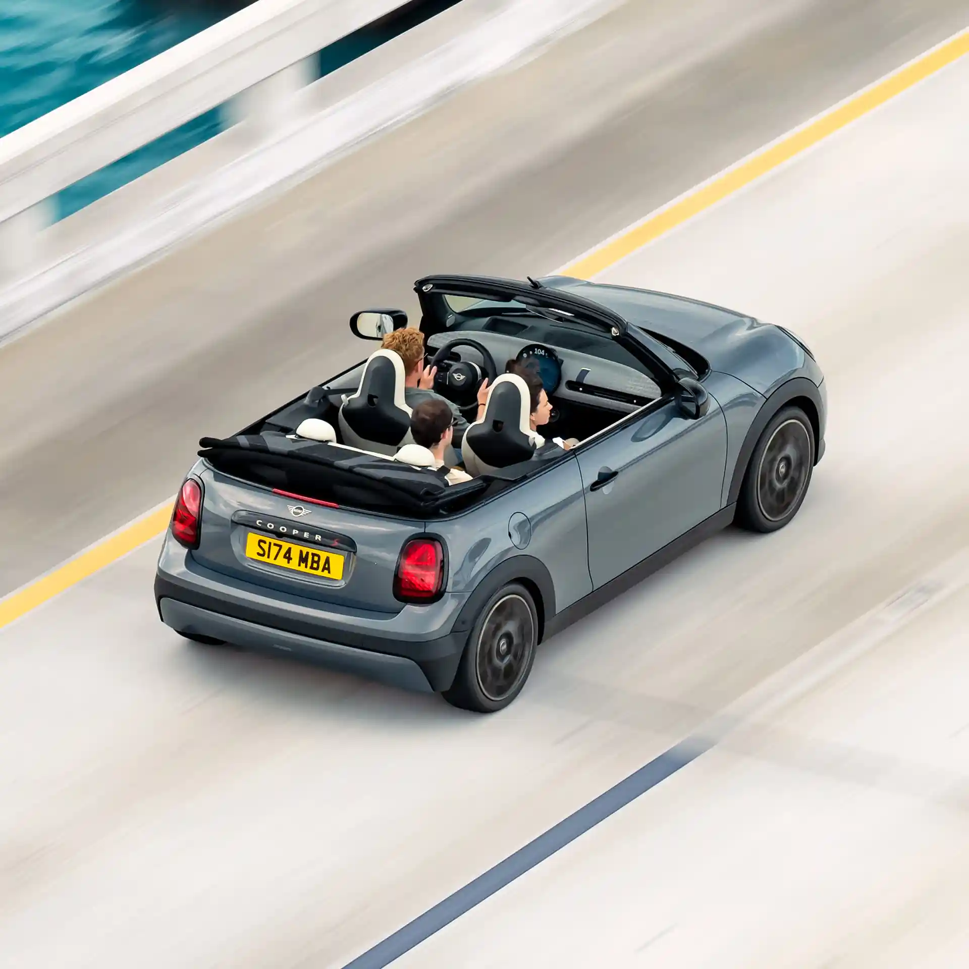 Achteraanzicht van boven op een rijdende MINI Cooper Cabrio op een weg