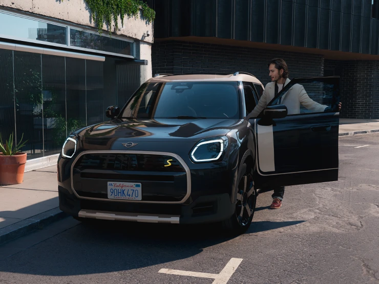 Vooraanzicht van de MINI Countryman Electric in Midnight Black met dak in Vibrant Silver op straat.