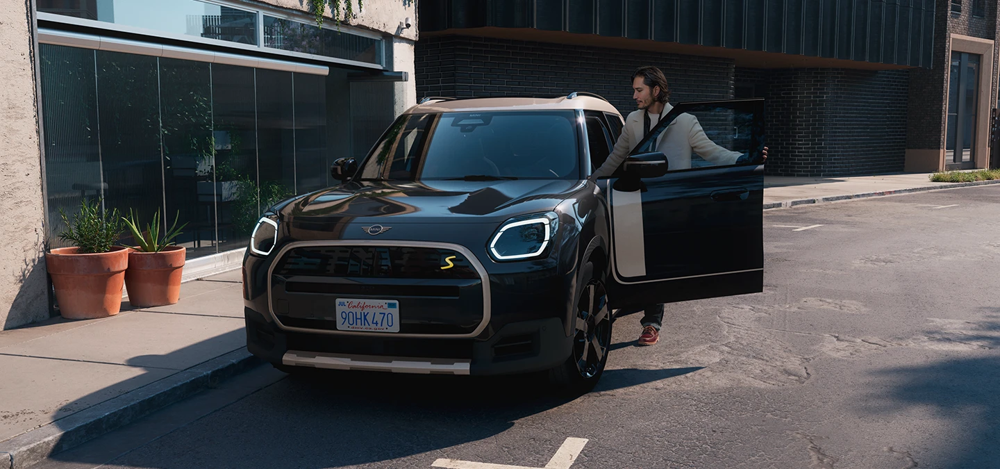 Vooraanzicht van de MINI Countryman Electric in Midnight Black met dak in Vibrant Silver op straat.