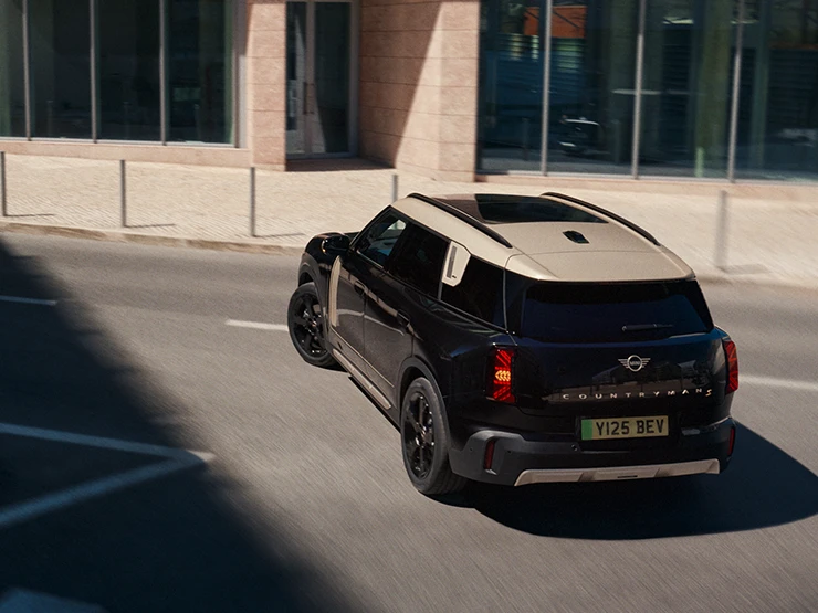 Bovenaanzicht van een parkerende MINI Countryman Electric in Midnight Black met dak in Vibrant Silver.