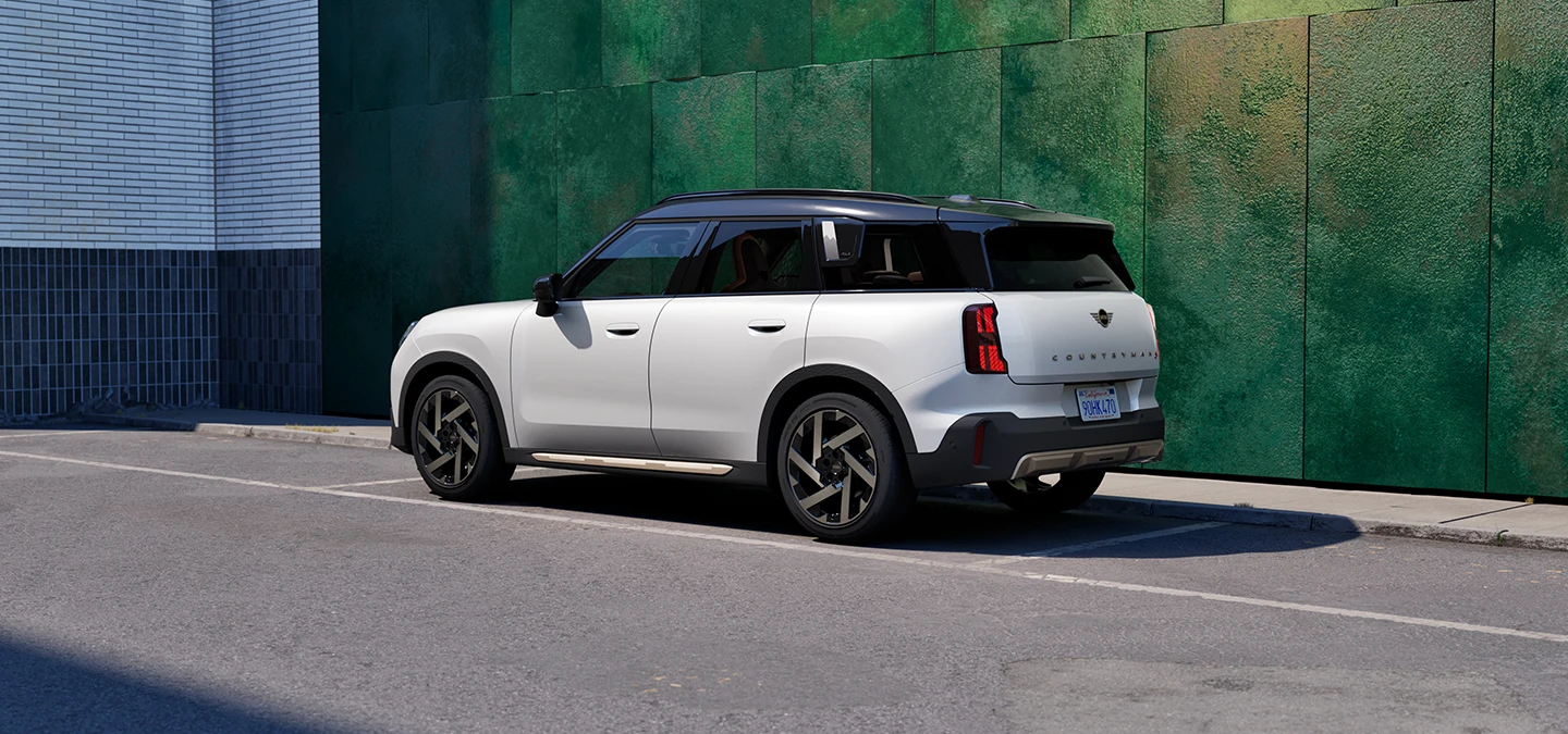 Zijaanzicht van de MINI Countryman in Nanuq White met dak in Black, in een straat.