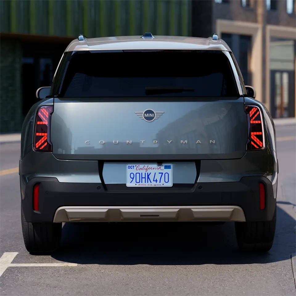 Achteraanzicht van een parkerende MINI Countryman in Smokey Green met dak in Vibrant Silver