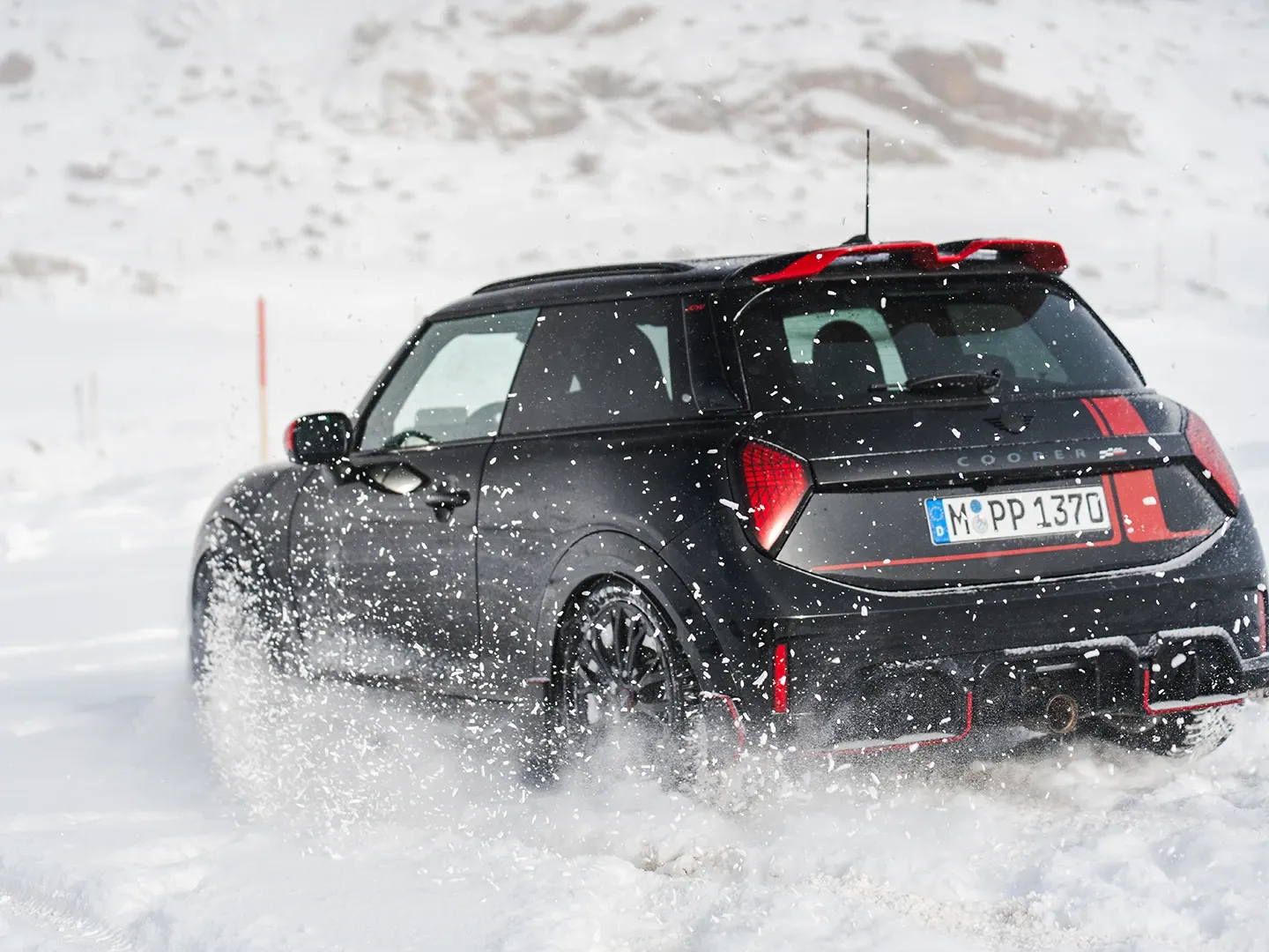 Achteraanzicht van een MINI Cooper JCW rijdend door de sneeuw