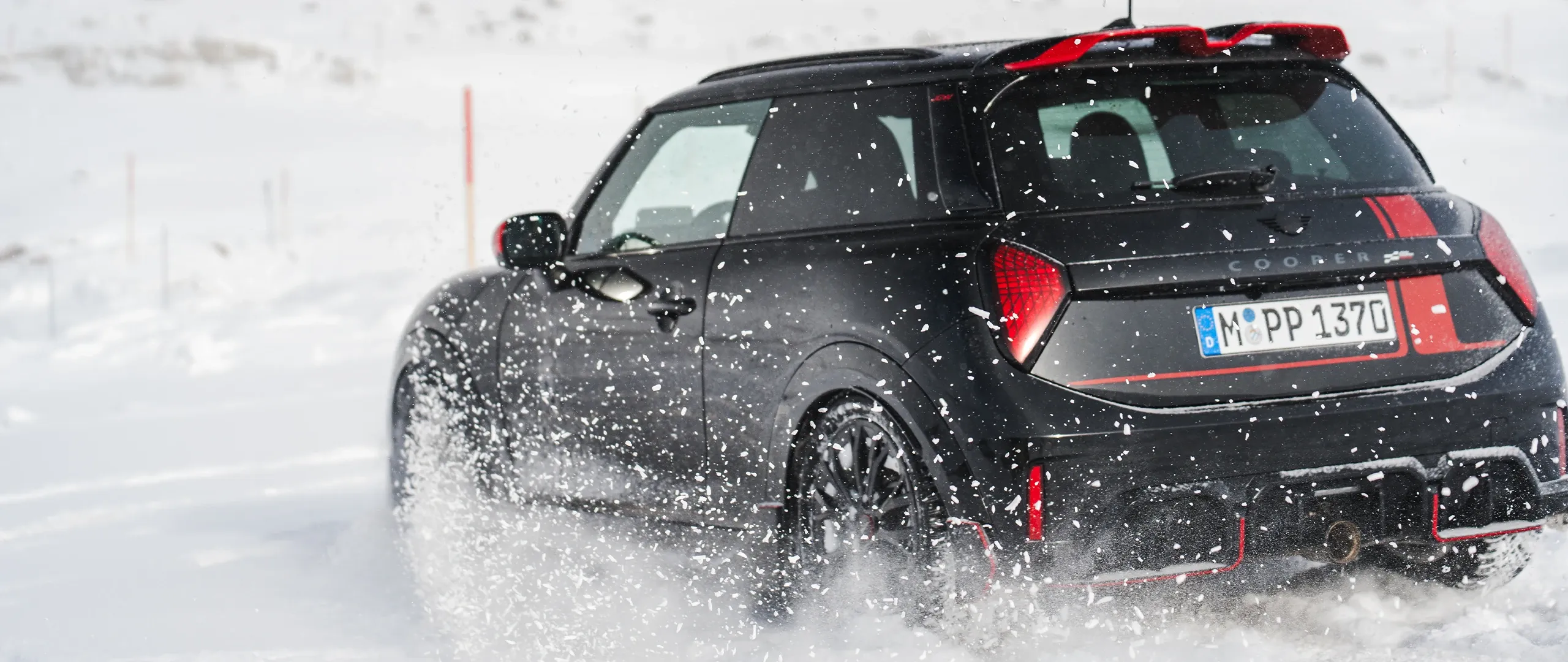 Achteraanzicht van een MINI Cooper JCW rijdend door de sneeuw