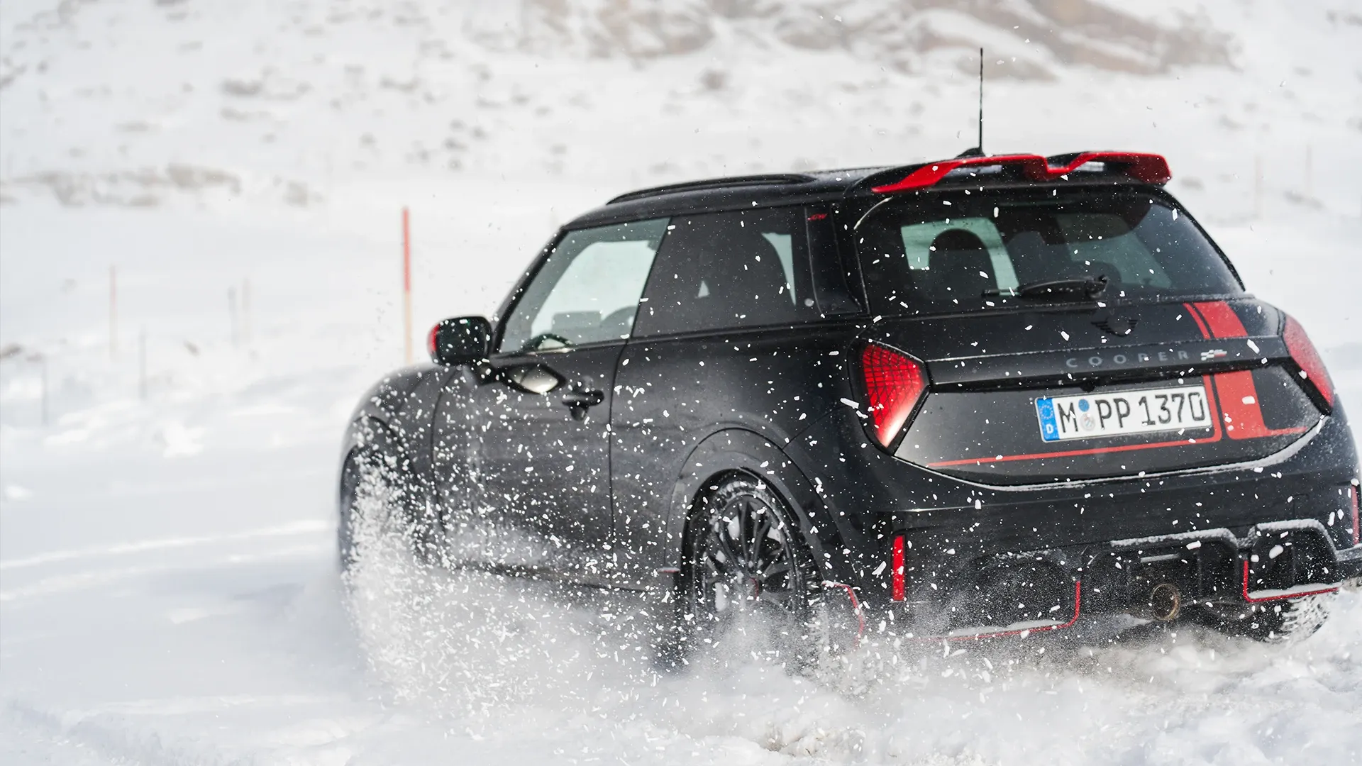 Achteraanzicht van een MINI Cooper JCW rijdend door de sneeuw