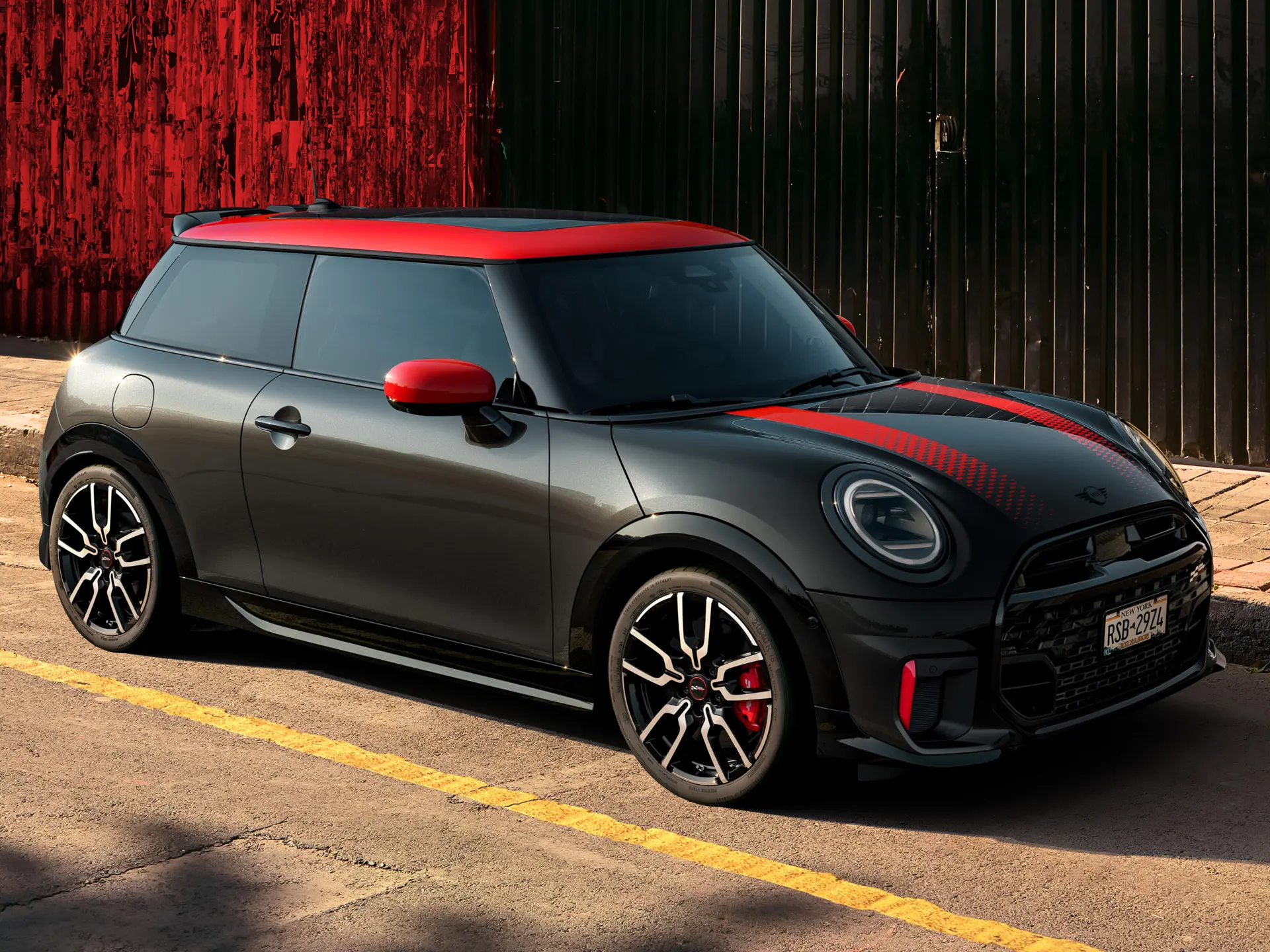 MINI John Cooper Works 3-deurs in Midnight Black met dak en buitenspiegelkappen in Chili Red en sportieve strepen in het rood, zijaanzicht, op straat geparkeerd.