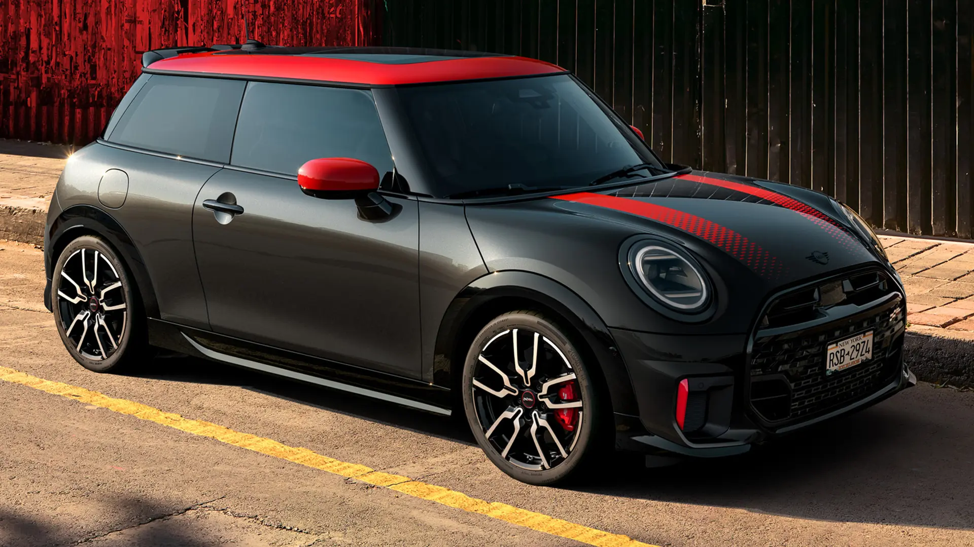 MINI John Cooper Works 3-deurs in Midnight Black met dak en buitenspiegelkappen in Chili Red en sportieve strepen in het rood, zijaanzicht, op straat geparkeerd.