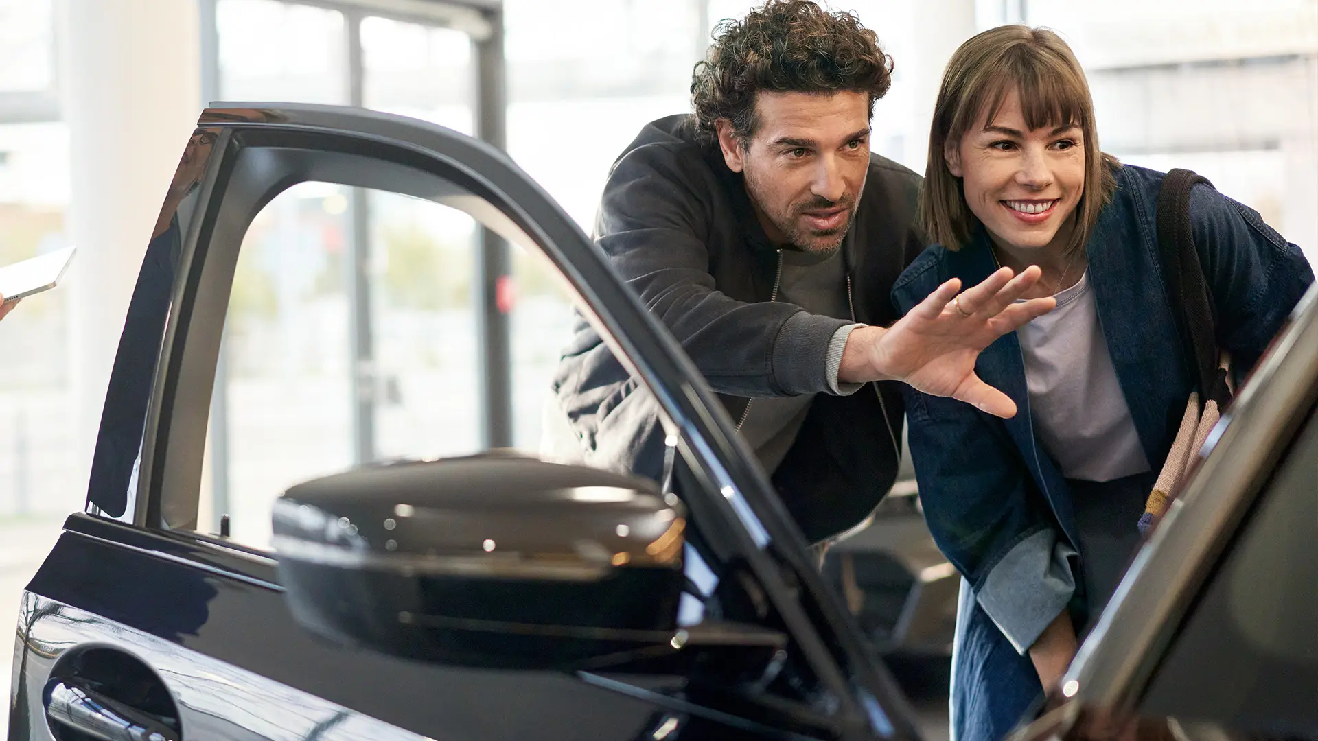 MINI in de showroom van de MINI dealer met een verkoopvertegenwoordiger die de klant adviseert en uitlegt wat de auto te bieden heeft.