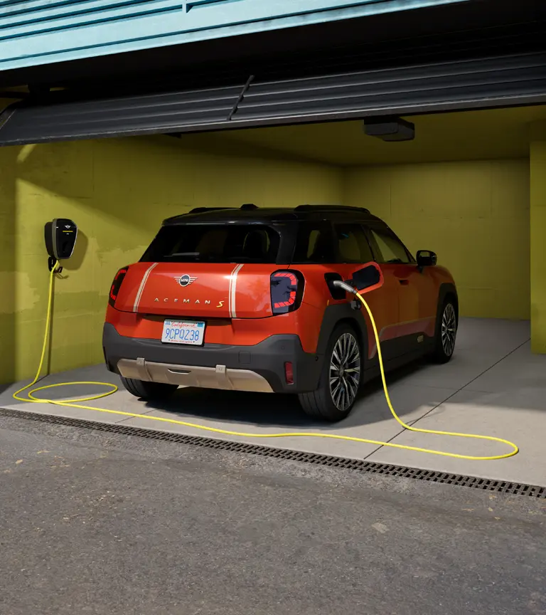Volledig elektrische MINI Aceman S wordt opgeladen met de MINI Wallbox Plus, achteraanzicht, geparkeerd in de garage.