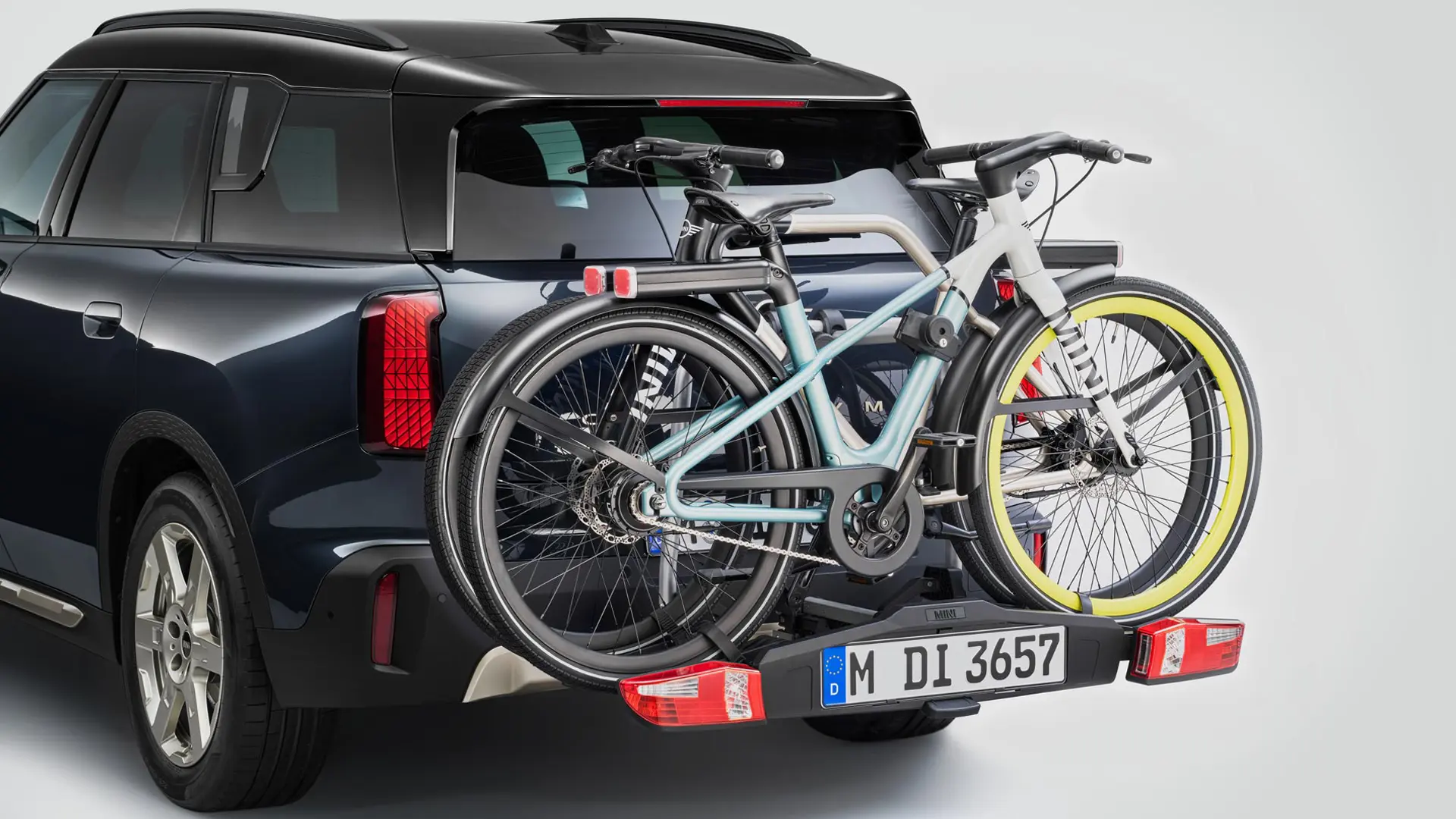 MINI Countryman in zwart uitgerust met de fietsendrager voor achterop met twee mountainbikes, achteraanzicht, rijdend over een bergweg.