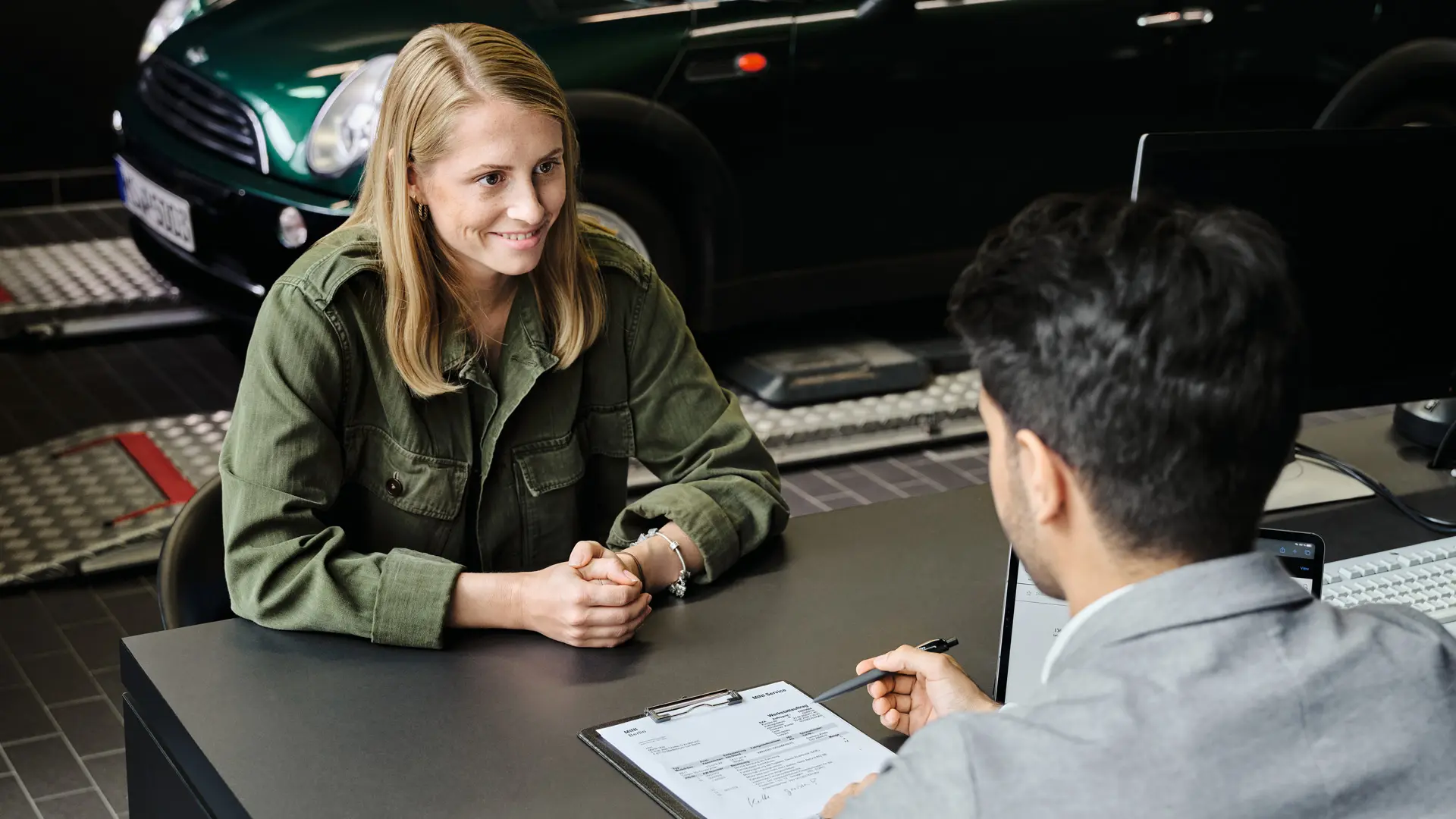 MINI dealer met een verkoopvertegenwoordiger die de klant adviseert over haar serviceopties, beiden zittend aan tafel.