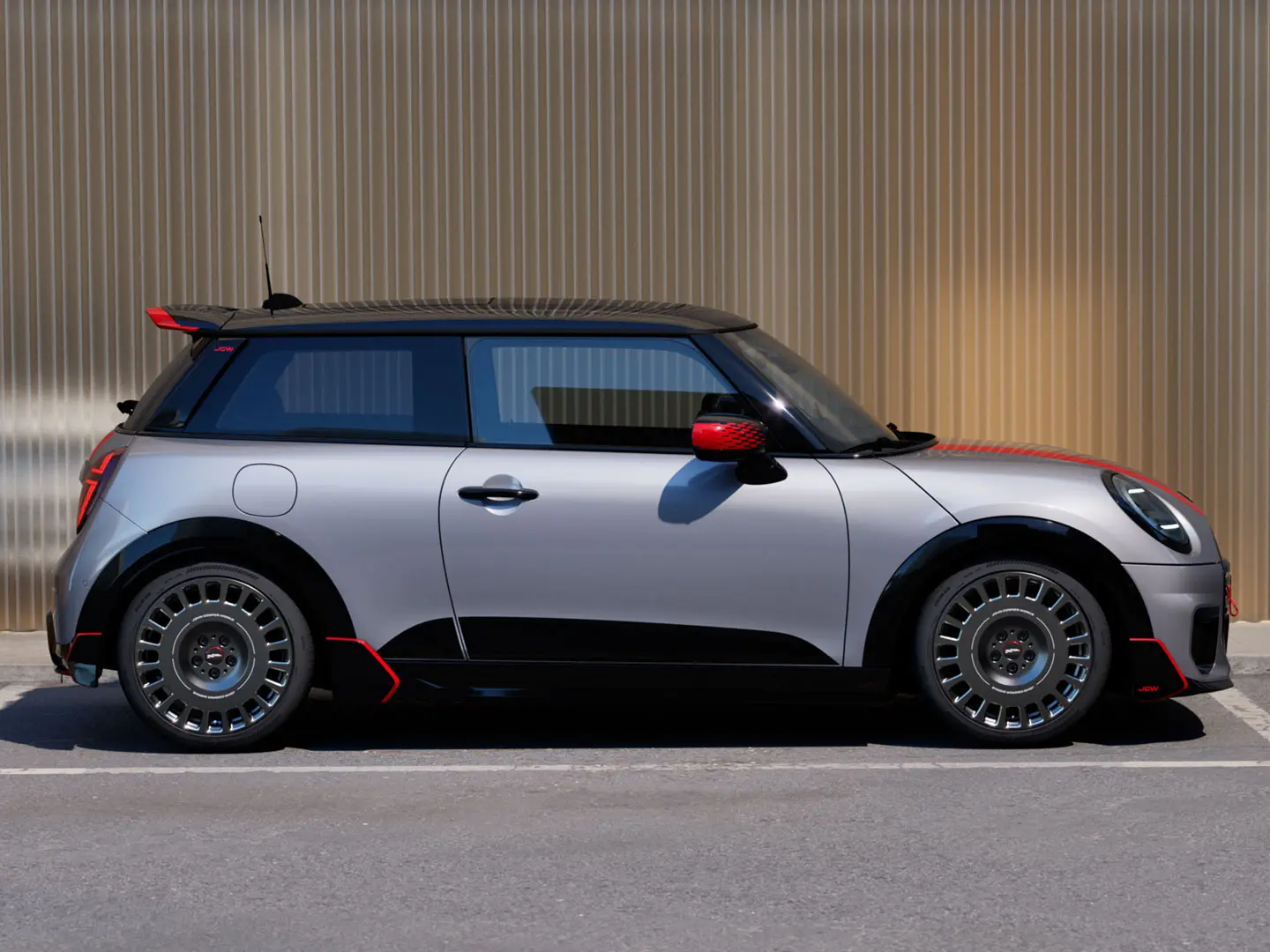 MINI Cooper 3-deurs in Melting Silver met John Cooper Works dakspoiler voor verbeterde aerodynamische eigenschappen – zijaanzicht.