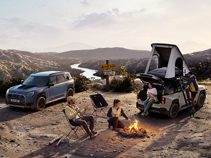 Foto van twee MINI Countryman Untamed Edition voertuigen op een berg bij zonsondergang.