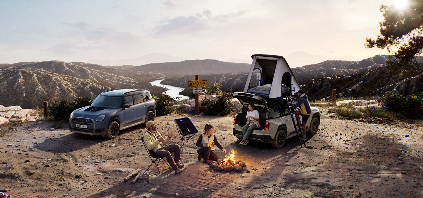 Foto van twee MINI Countryman Untamed Edition voertuigen op een berg bij zonsondergang.