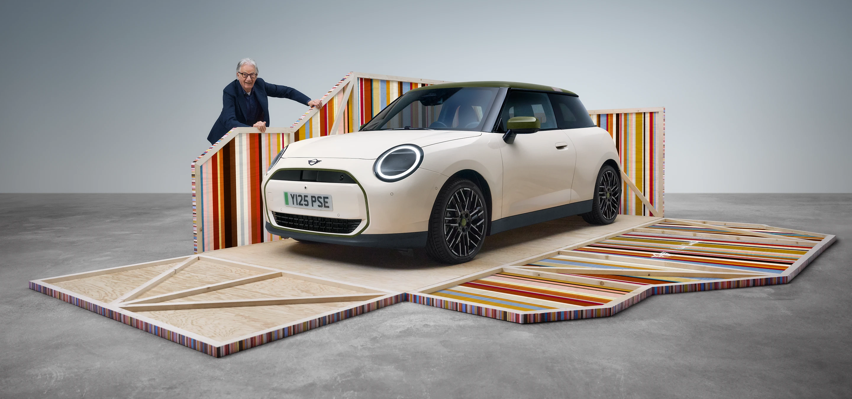 Vooraanzicht van de volledig elektrische MINI Cooper Paul Smith Edition in de kleur Inspired White met ontwerper Paul Smith
