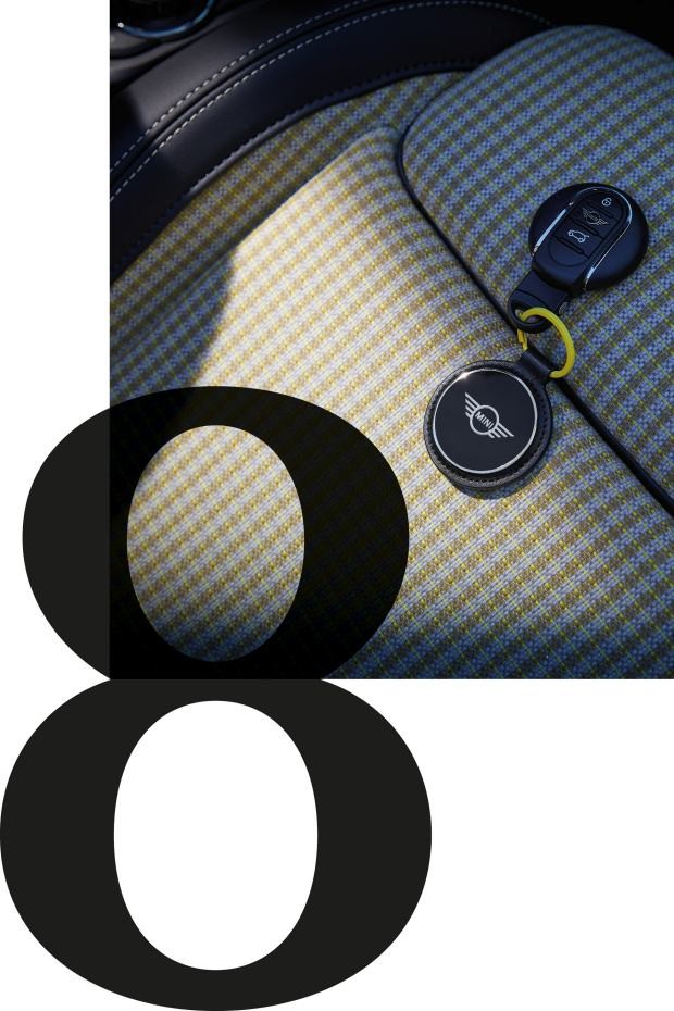 Afbeelding van de innovatief en duurzaam geproduceerde MINI Bracenet Keyring liggend op een autostoel met geruit motief.